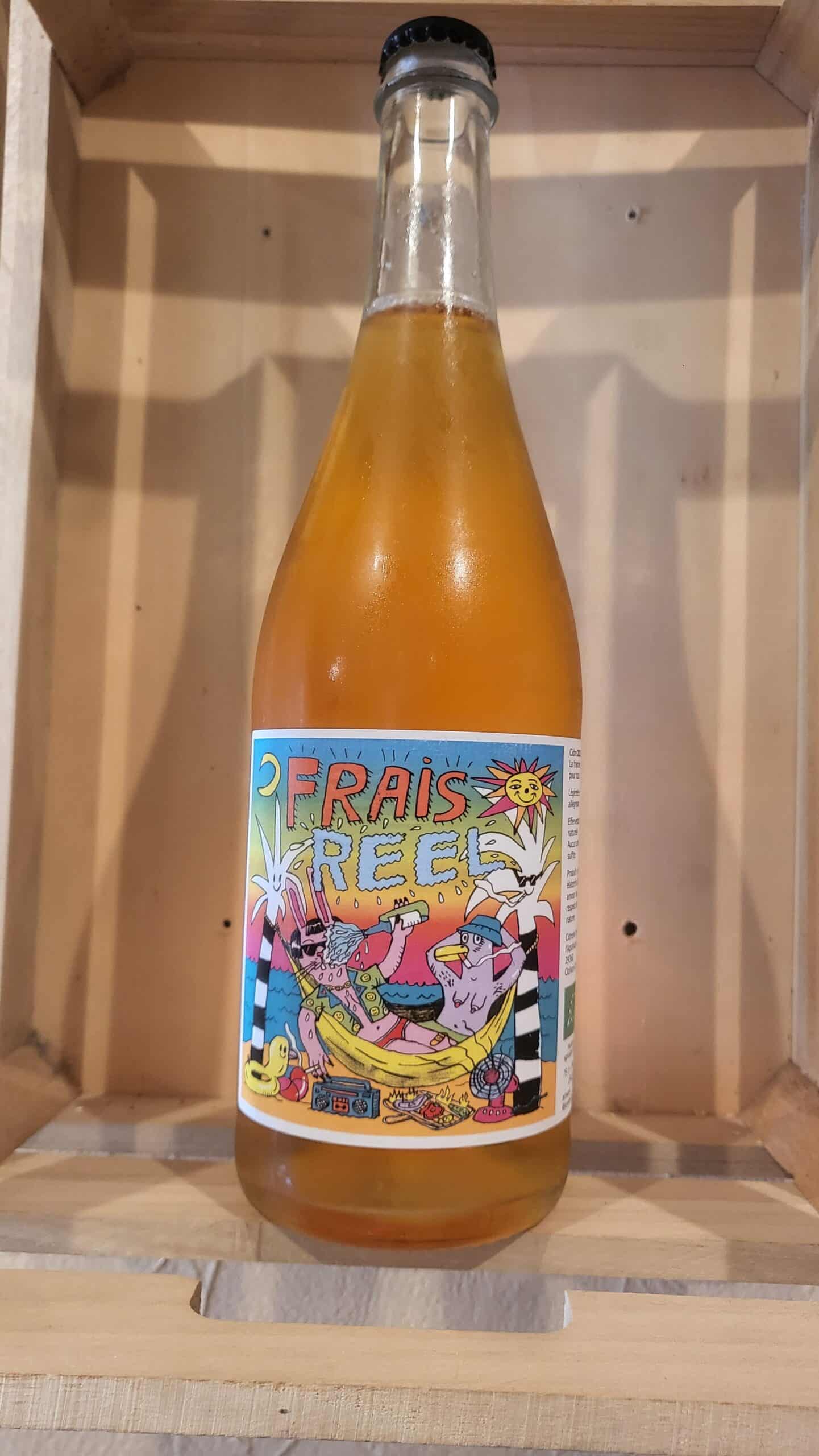 Bouteille de cidre pétillant "FRAIS REEL" à l'étiquette cartoon estivale (lapin, canard) sur bois clair. Boisson orangée.