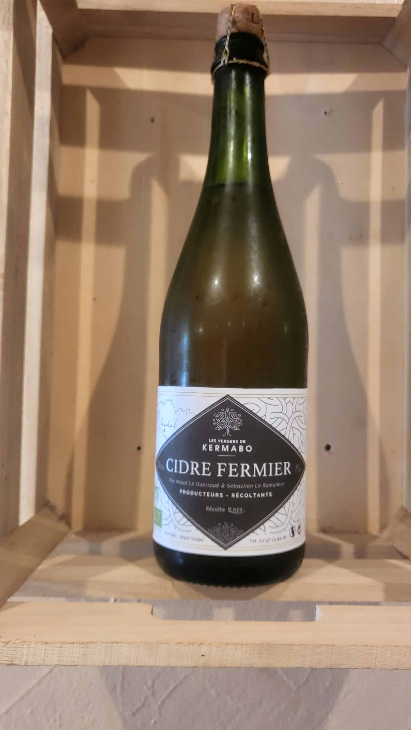 Bouteille de Cidre Fermier Kermabo Récolte 2023 dans une caisse en bois. Le cidre est produit par Maud Le Guerroué & Sébastien Le Romancer.