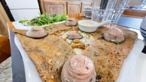 Galette de sarrasin garnie de viande, fromage fondu, oignons caramélisés, avec pâté en spirale, salade et sauce. Bol "Val de Rance".